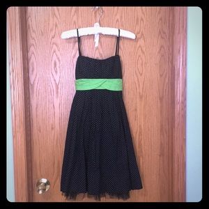 Black and white polka dot dress with a green sash.